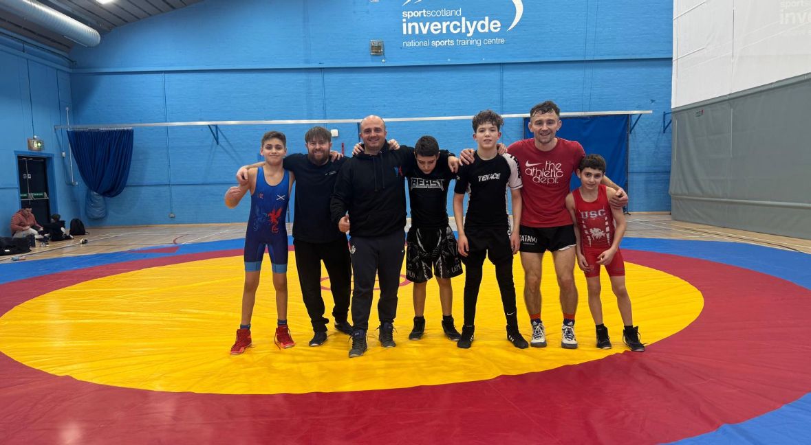 Photo de groupe des athlètes et coachs devant le logo sportscotland Inverclyde