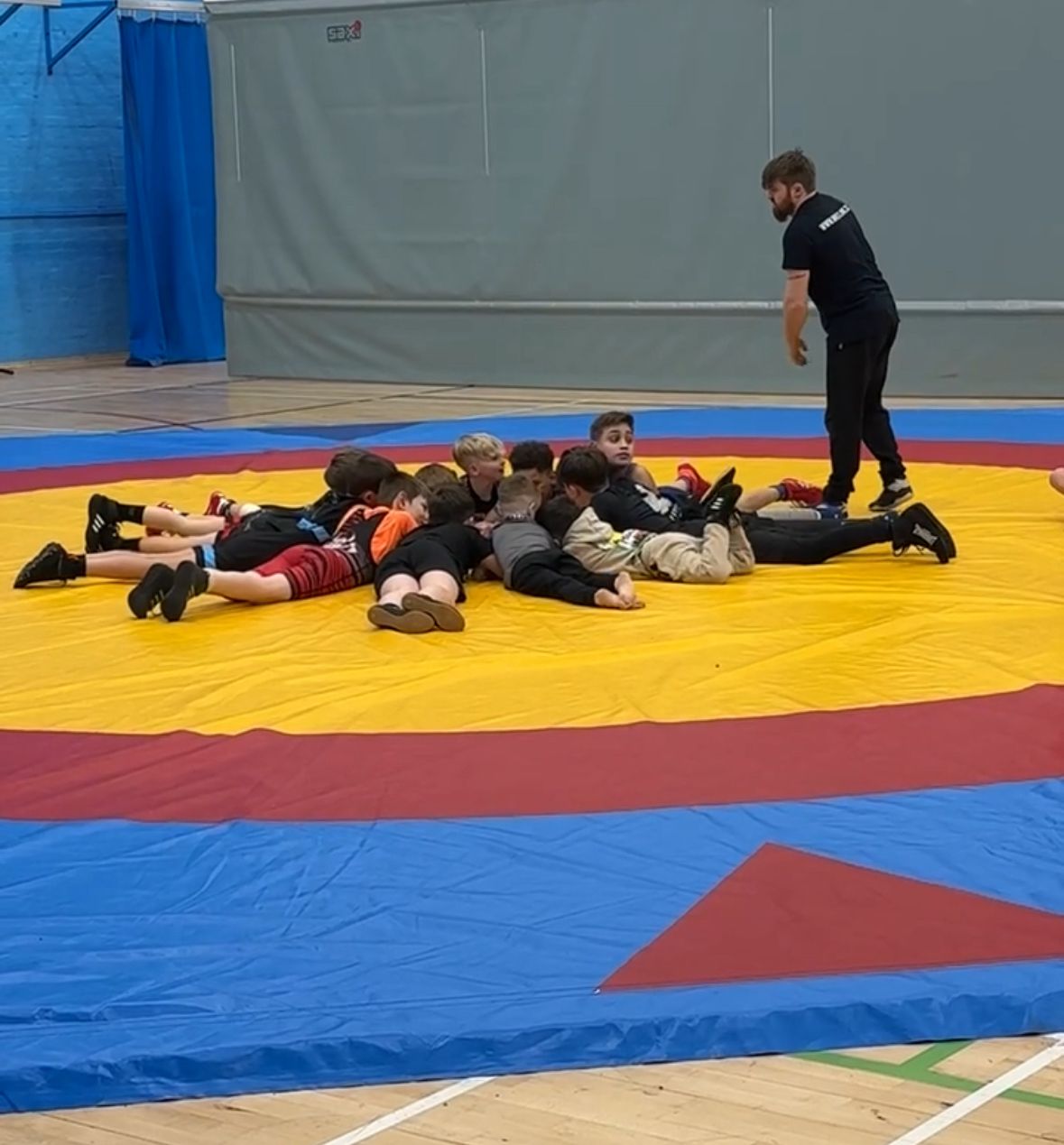 Enfants en tenue de lutte allongés en cercle sur le tapis d'entraînement